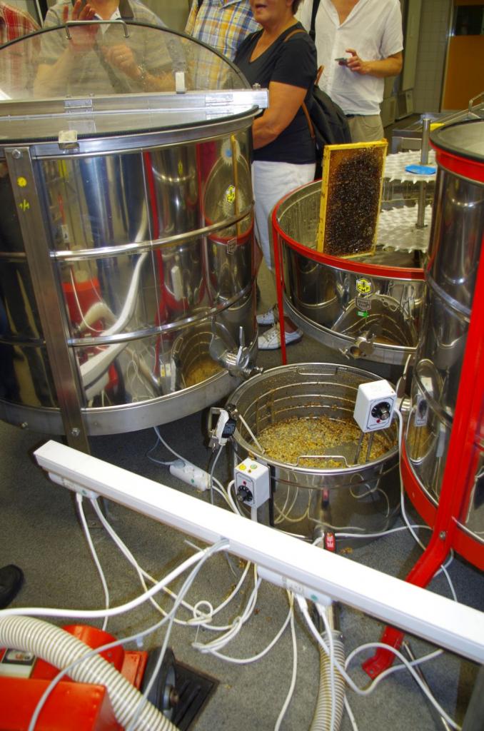 Die Schleudern und das Wabenkarusell entleeren sich in ein Sammelgefäß, das den Honig temperiert hält. Von dort aus pumpt die Honigpumpe in die Siebgefäße. Alle Sammelbehälter sind mit Füllstandsgebern versehen, die die Pumpe abschalten falls Honig über den Rand tritt.